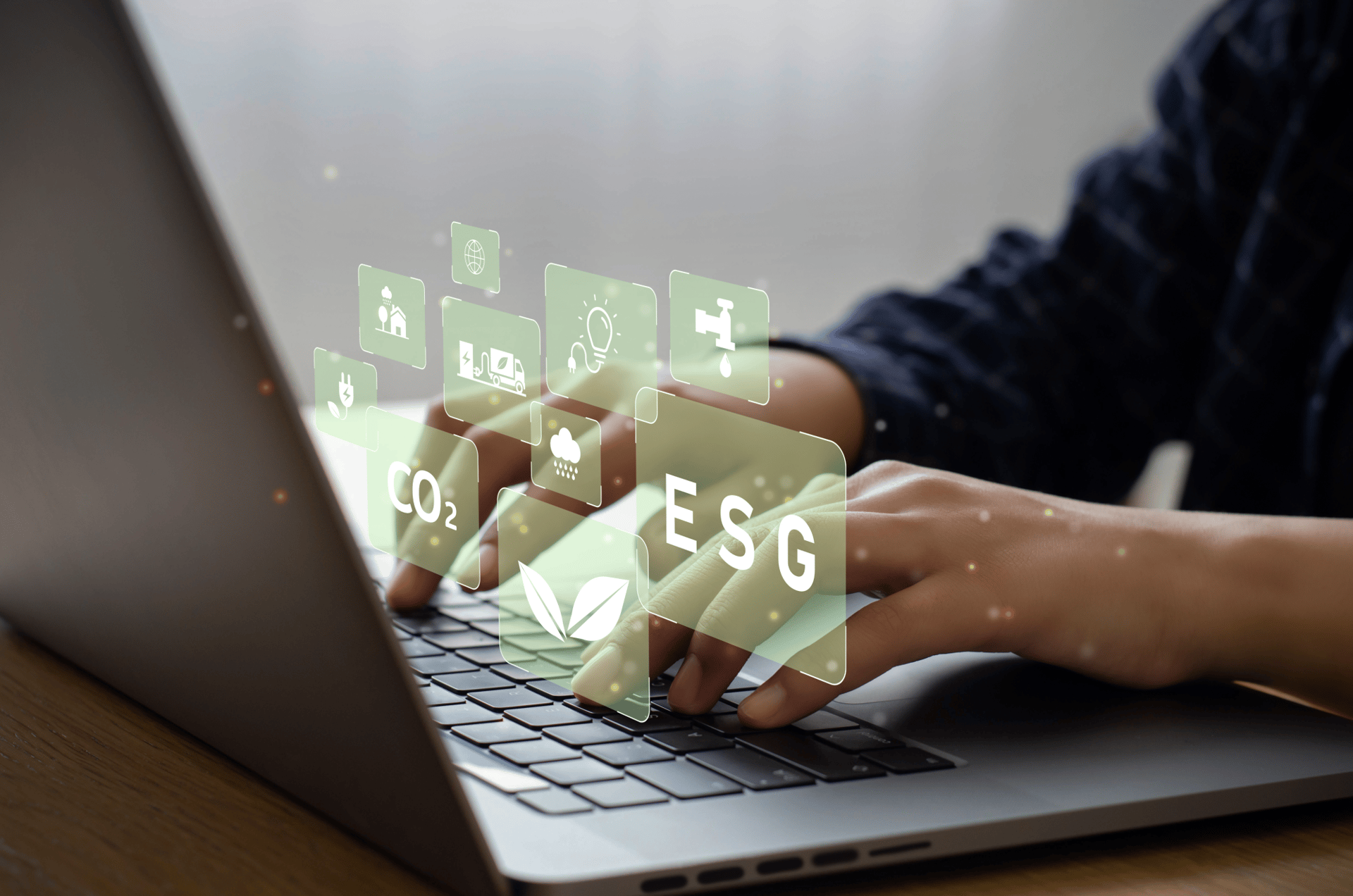 A person typing on a laptop with floating icons representing sustainability concepts such as CO2 and ESG.