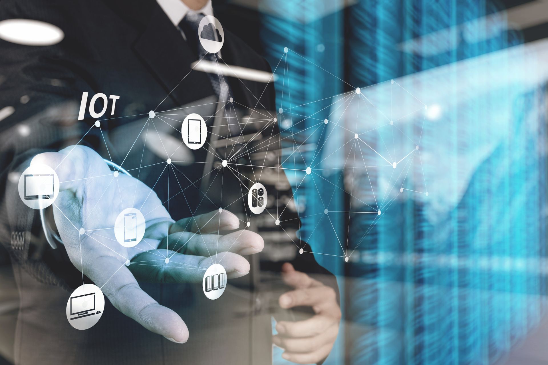 A business professional in a suit gestures towards a floating network of icons representing the Internet of Things (IoT), including various devices like smartphones, laptops, and smart appliances. The background features a digital interface with data visualization elements.