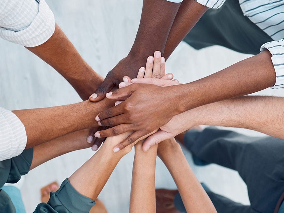 A diverse group of hands stacked on top of each other in a display of teamwork and unity.