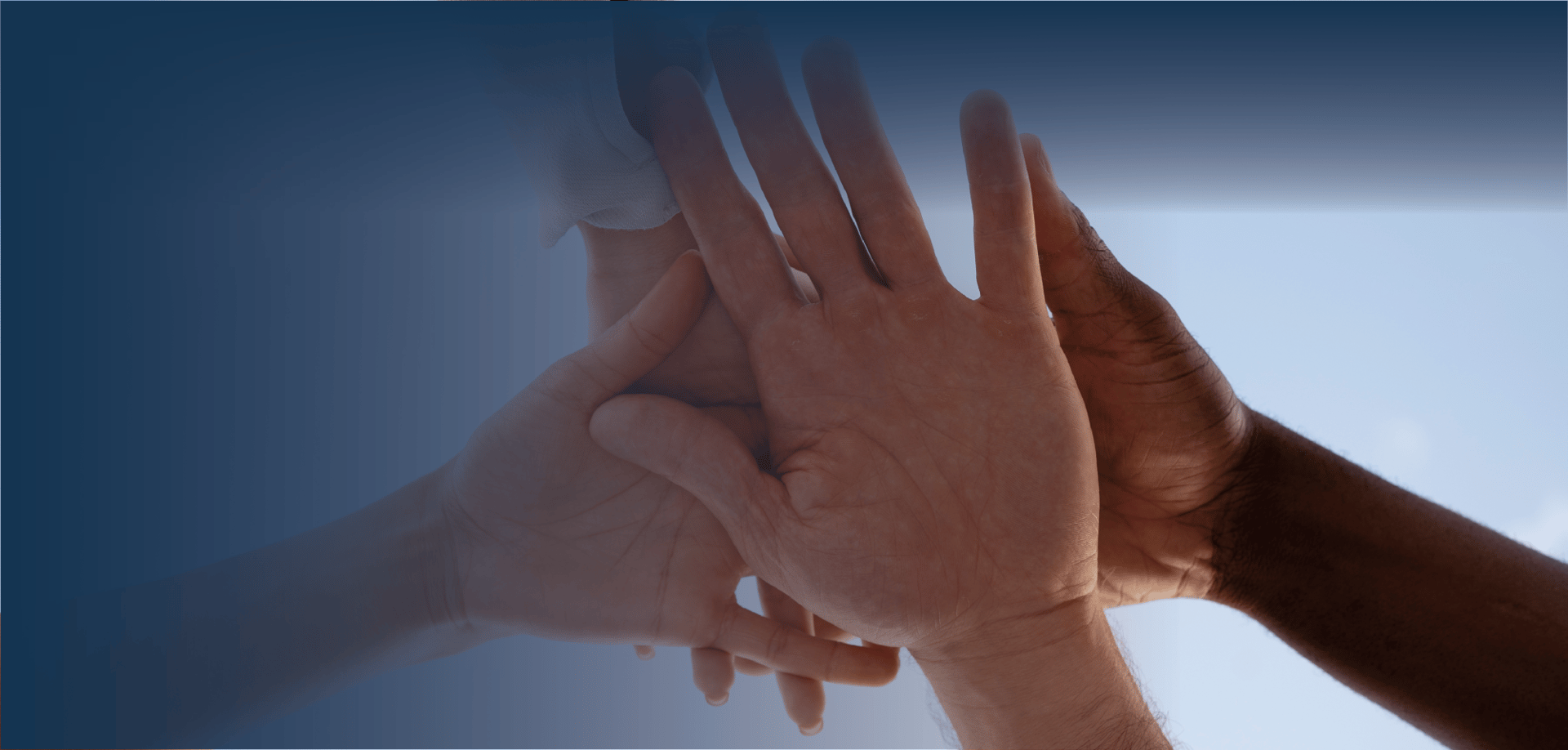 Hands of different skin tones reaching toward each other against a soft blue background, symbolizing unity and connection.
