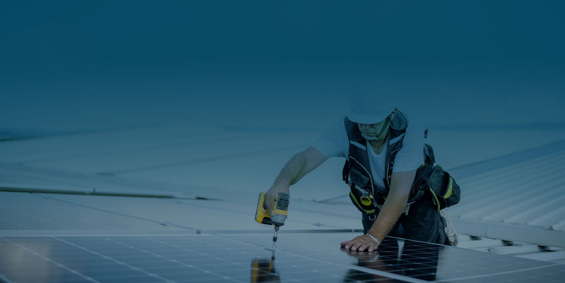 Ein Handwerker installiert eine Solarpanel auf einem Dach und verwendet dabei eine Akku-Bohrmaschine.