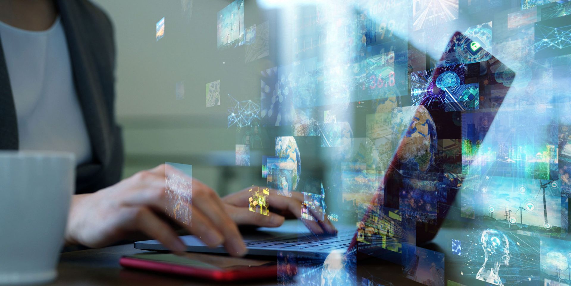 A person typing on a laptop with holographic images and digital data visually overlaying the scene, creating a futuristic ambiance.