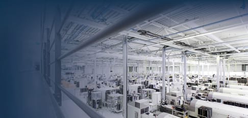Ein weitläufiger, moderner Produktionsraum mit mehreren Maschinen und Einrichtungen. Die Decke ist hoch, und die Beleuchtung ist hell, was einen sauberen und organisierten Eindruck hinterlässt.