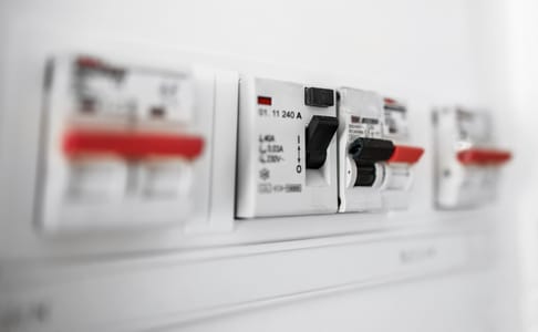 Sicherungskasten mit mehreren elektrischen Schaltern und Sicherungen. Die Schalter sind beschriftet und einige sind in der Position „Ein“.