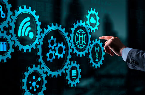 Ein Menschlicher Hand zeigt auf leuchtende Zahnräder, die Symbole für Technologien wie Cloud, Netzwerk, Funk und Daten darstellen. Der Hintergrund ist dunkel, mit einer digitalen Schnittstelle.