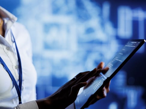 Eine Person hält ein Tablet und verwendet es, während sie von einer digitalen Hintergrundgrafik umgeben ist. Die Hände sind konzentriert auf den Bildschirm gerichtet.